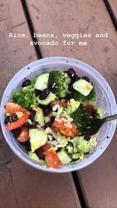 a plastic bowl filled with vegetables on top of a wooden table