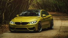 a yellow car parked on the side of a dirt road in front of some trees