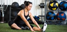 a woman sitting on the ground working out with her feet in front of an exercise ball rack