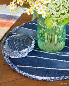 a vase filled with flowers sitting on top of a blue table cloth covered placemat