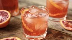 grapefruit cocktail with ice and garnish on wooden table next to sliced grapefruits