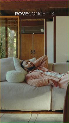 a man laying on top of a couch covered in a pink blanket and holding a pillow