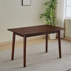 a wooden table sitting on top of a carpeted floor next to a potted plant