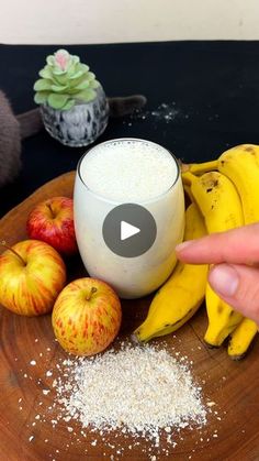 a person pointing at an apple and banana smoothie on a plate with other fruit