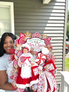 a woman holding up a christmas wreath made out of candy canes and gingerbreads