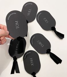 a hand is holding several black fan shaped tags