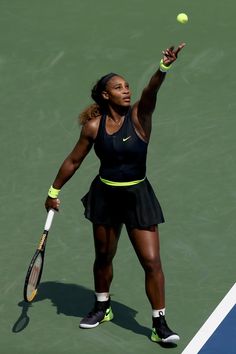 a woman holding a tennis racquet on top of a tennis court with a ball in the air