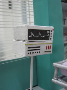 an electronic device sitting on top of a metal stand in front of a green wall