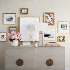 a dresser with flowers and pictures on the wall