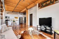 a living room filled with furniture and a flat screen tv on top of a wooden floor