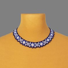 a blue and white beaded necklace on a mannequin neckline with an orange shirt underneath