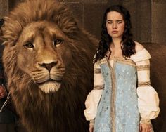 a woman standing next to a large lion