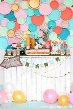 a dessert table with balloons, plates and confetti on the wall behind it