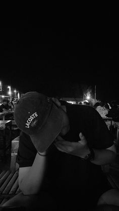 a man sitting on top of a wooden bench next to another person wearing a hat