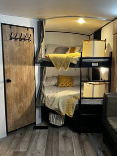 bunk beds in a small room with wooden floors and white walls, along with yellow throw pillows