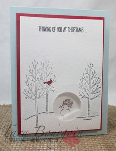 a christmas card with a red bird sitting on a plate in the middle of trees