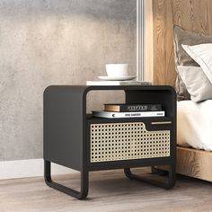 a bedside table with books and a cup on it next to a bed in a bedroom