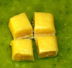 four cubes of food sitting on top of a green surface with water in the background