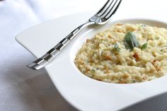 a white plate topped with riso and garnished with green leaves next to a fork