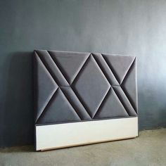 an upholstered headboard with white and grey panels on the sides, against a gray wall