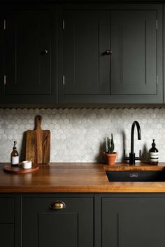 a kitchen with black cabinets and wooden counter tops, including a sink in the center