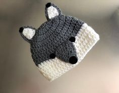 a crocheted hat with a fox on it's side hanging from a hook