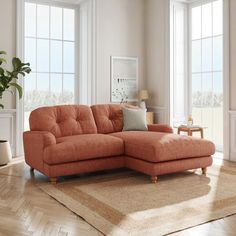 an orange sectional sofa in a living room with large windows and rugs on the floor