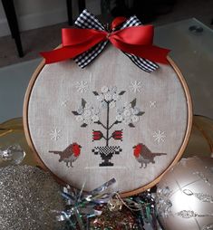 a cross - stitch christmas ornament with two birds on it and red ribbon