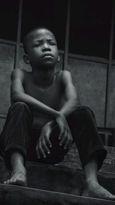 a black and white photo of a young boy sitting on steps