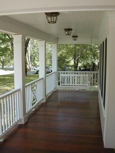 an empty porch with white railings and wood flooring on the side of it