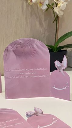 pink bags with white butterflies on them sitting on a table in front of a flower vase