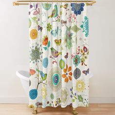 the shower curtain is decorated with colorful flowers and birds on white fabric, along with a bathtub