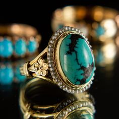 Description This beautiful, intricately crafted ring features a striking turquoise cabochon surrounded with a halo of delicate seed pearls. Buttery and vibrant 14k yellow gold brings out the stones' gorgeous natural hues of turquoise and cream, lending a bright, ethereal quality to this beautiful ring. Featuring a handcarved floral detail on each shoulder, this lovely piece is ready to live another lifetime with you. 14k yellow gold Natural Turquoise Cultured freshwater seed pearls The stone mea Turquoise Cabochon Heirloom Ring, Heirloom Yellow Gold Turquoise Cabochon Ring, Victorian Turquoise Gemstone Jewelry, Fine Jewelry Turquoise Cabochon Ring In 14k Gold, Fine Jewelry 14k Gold Turquoise Cabochon Ring, Turquoise Oval Cabochon Wedding Jewelry, 14k Gold Turquoise Cabochon Ring, Heirloom Turquoise Cabochon Jewelry, Heirloom Style Turquoise Cabochon Wedding Ring