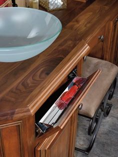 a bathroom sink sitting under a wooden counter next to a bowl on top of a table