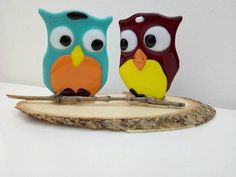 two colorful owls sitting on top of a piece of wood