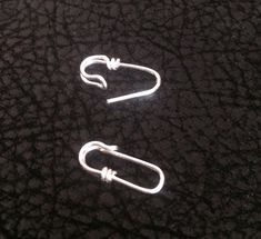 two white paper clips sitting on top of a black surface