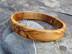 handmade Bracelet Bangle made out of fine olive wood Diameter inside 6,5 cm ( 2,56 inch) large ~1.5 cm ( 0,59 inch) the olive wood is finely sanded and oiled with olive oil naturally the grain of the olive wood can vary from item to item , but in any case you will get a olive wood bracelet with beautiful grain This bangles are turned by us from a piece of olive wood. Handmade in Portugal In our Shop you can find more earrings , rings and necklaces made out of olive wood ! Handmade Natural Color Bangle Bracelets, Handmade Natural Color Bangle Bracelet, Natural Bangle Bracelets As Gift, Natural Color Bangle Bracelets As Gift, Natural Bangle Bracelets For Gifts, Natural Color Bracelet Jewelry Gift, Handmade Natural Wood Bracelets As Gift, Natural Wood Bracelet As A Gift, Natural Wood Bracelet Jewelry Gift