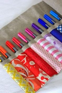 several different colored pens are lined up on a piece of fabric with various patterns and colors