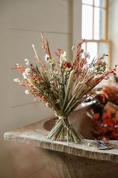 dried flowers sit in a vase on a table