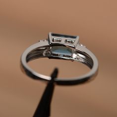 It is a London blue topaz ring. The main stone is 6mm*8mm emerald cut, weight about 2.0 carats. The basic metal is sterling silver and plated with rhodium. To change the metal to a solid gold (white/rose) or platinum is also available, please ask for a quotation if you want. You can also go to my shop Home for more elegant rings: https://www.etsy.com/shop/godjewelry?ref=hdr_shop_menu More topaz rings: https://www.etsy.com/shop/godjewelry?ref=hdr_shop_menu§ion_id=20715039 Customization is always Silver Ring With Rectangular Blue Topaz, Silver Rings With Rectangular Blue Topaz, Silver Blue Topaz Ring With Rectangular Stone, Fine Jewelry Blue Topaz Rectangular Rings, Silver Topaz Ring With Rectangular Blue Stone, Emerald Cut Cubic Zirconia Topaz Ring With Halo Setting, Square-cut Blue Topaz Gemstone Jewelry, White Gold Blue Topaz Baguette Cut Ring, Square Cut Blue Topaz Gemstone Jewelry