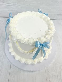 three tiered cake with blue ribbon and bow on white wooden table top, ready to be served