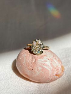 a close up of a ring on top of a pink rock with white and green crystals