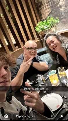 three people sitting at a table with food and drinks