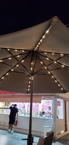 an umbrella with lights on it in front of a store