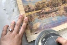 someone is painting a landscape on wood with acrylic paint and watercolors