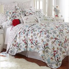 a white bed with christmas decorations on the comforter and pillow cases in front of it