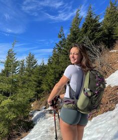 a woman hiking in the snow with her backpack and skis on, smiling at the camera