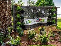 a couch sitting on top of a lush green field next to a wooden fence and trees