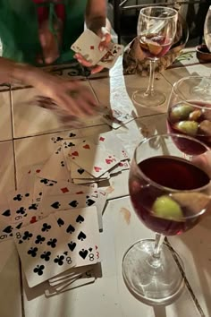 people are playing cards and drinking wine at a table