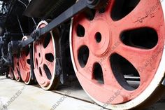 the wheels of an old steam locomotive are red and black, with white spokes